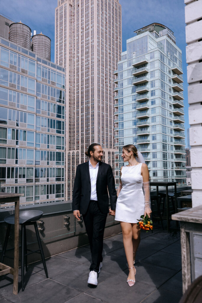 Couple standing on the Arlo Hotel rooftop with the Empire State Building towering in the background, capturing a romantic pre-wedding moment in NYC.