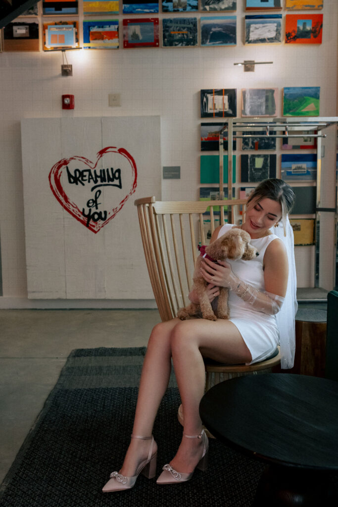 Bride in her wedding dress playing with her puppy in the Arlo Hotel, capturing a joyful and candid moment before the ceremony