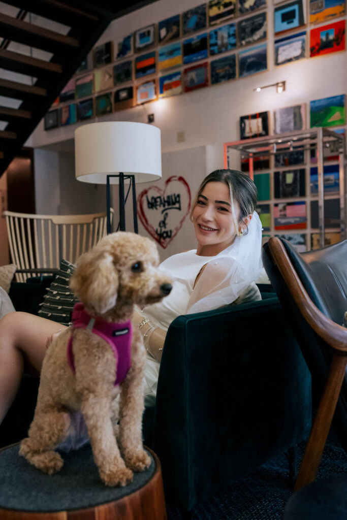 Bride in her wedding gown playing with her puppy at the Arlo Hotel, capturing a tender and joyful pre-ceremony moment
