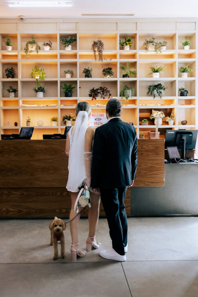 Couple standing together at the front desk of the Arlo Hotel, capturing a candid and stylish moment before their wedding.
