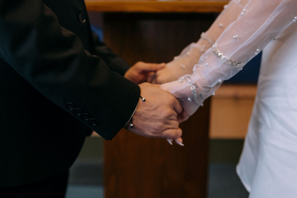 Couple holding hands during their wedding ceremony at Manhattan City Hall, sharing an emotional moment in NYC.