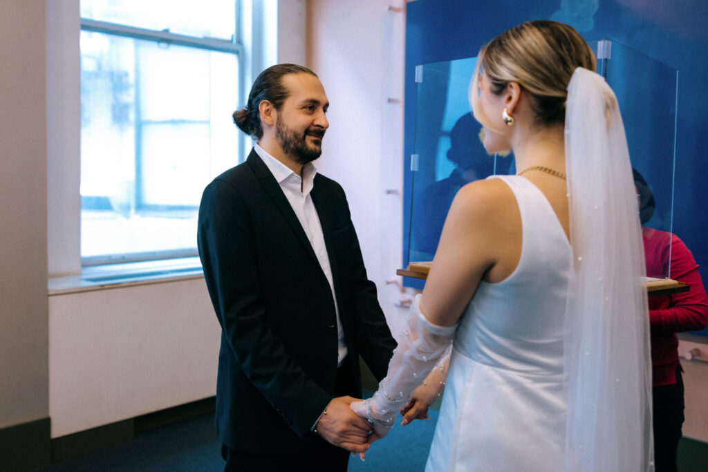 Couple holding hands during their City Hall wedding ceremony in Manhattan, NYC, capturing a heartfelt and intimate moment