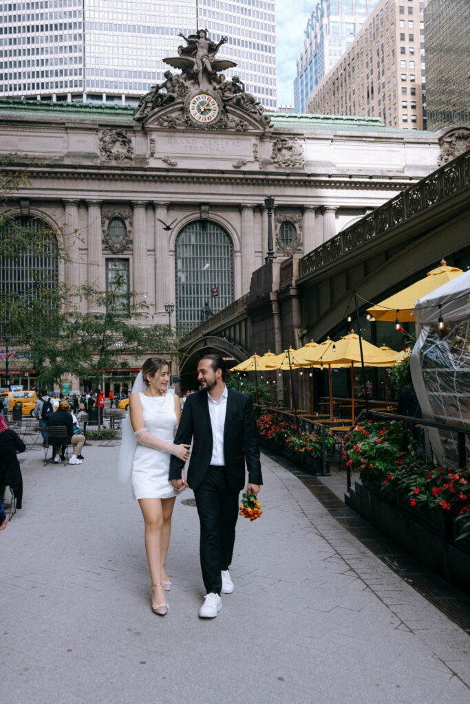 Couple walking hand-in-hand by Grand Central Terminal, capturing a romantic moment amid the iconic architecture of NYC.