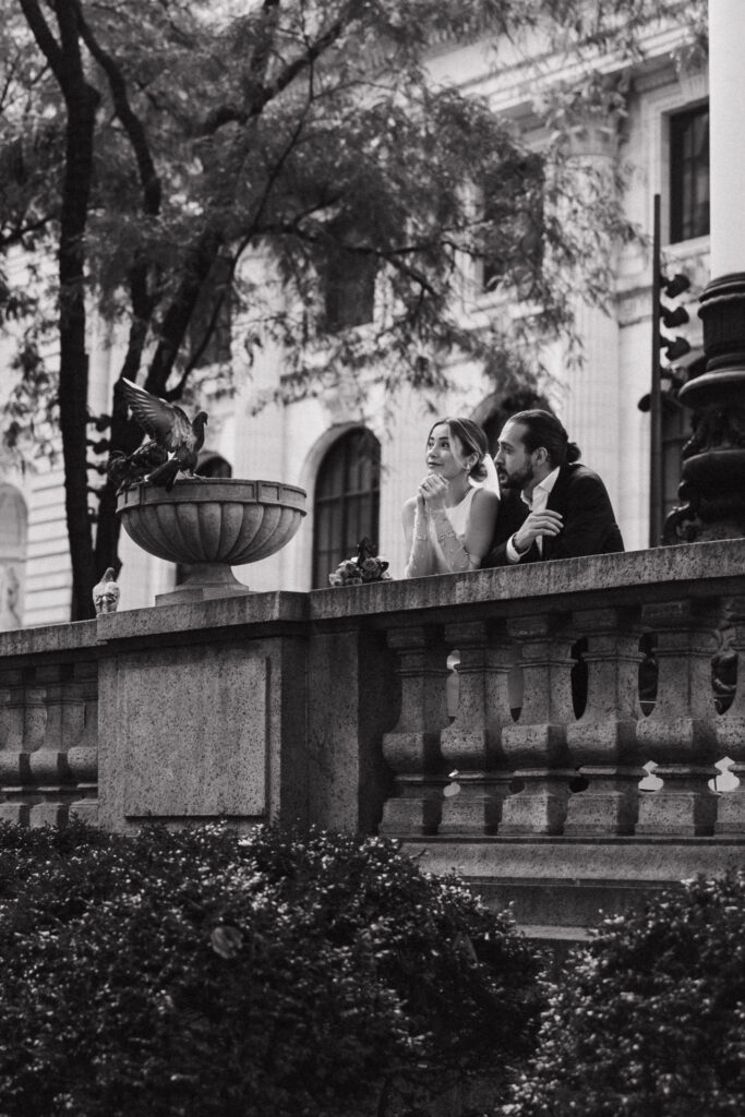 Newlywed couple by the New York Public Library with a dove flying overhead, symbolizing love and peace on their special day