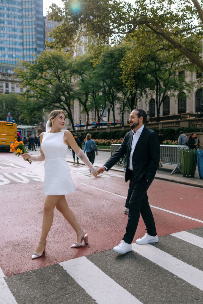 Couple crossing the crosswalk in Midtown, bathed in sunlight and sharing smiles, capturing a joyful moment in the heart of NYC.