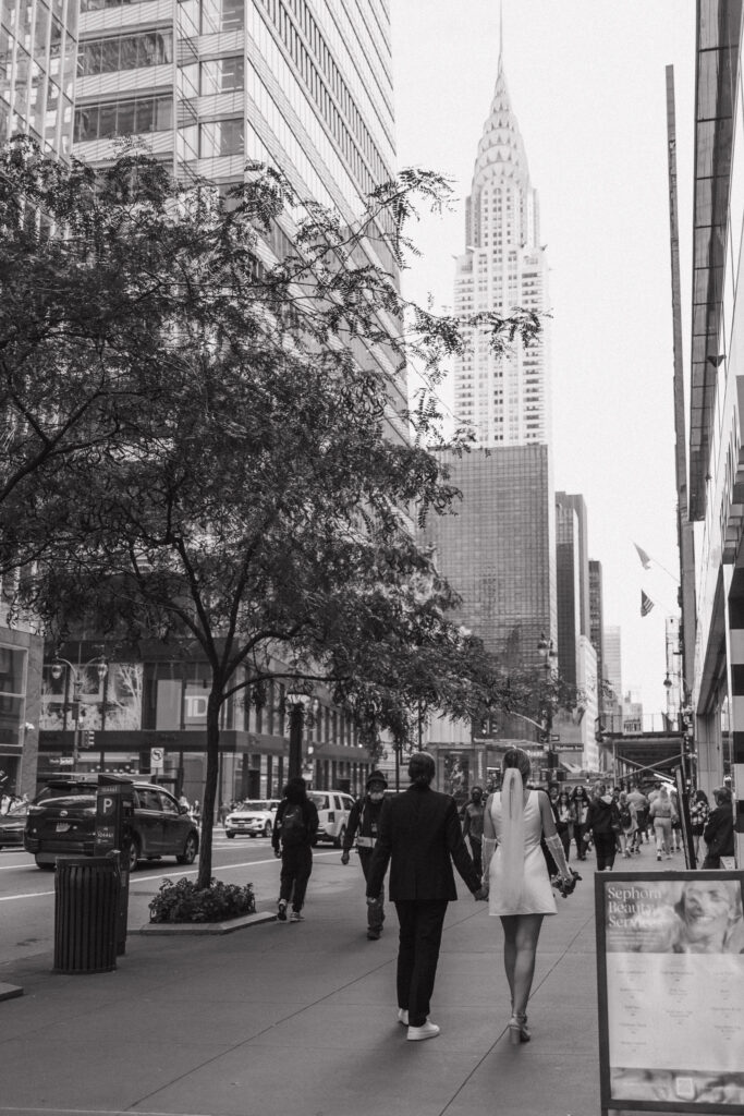 Couple laughing together with the Chrysler Building towering behind them, capturing joyful moments in a vibrant NYC setting.