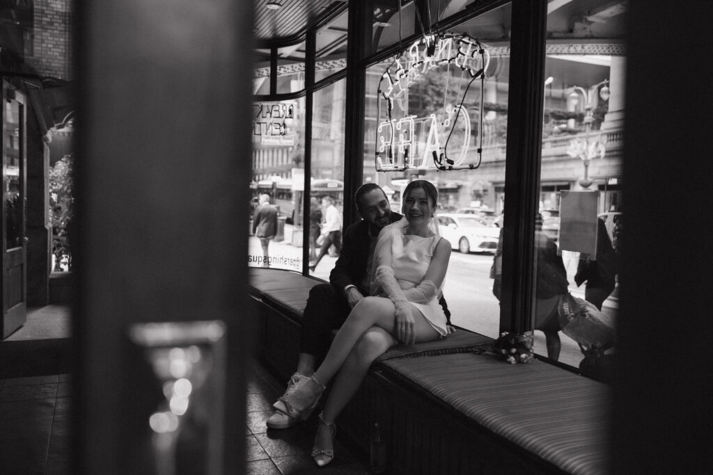 Couple gazing into each other's eyes at a café, surrounded by the cozy ambiance of NYC, capturing a romantic moment.