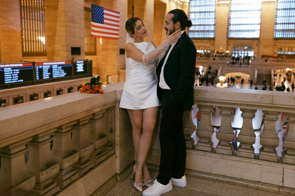 Couple celebrating their elopement with playful poses at Grand Central Terminal, showcasing their love against the backdrop of NYC's architectural beauty