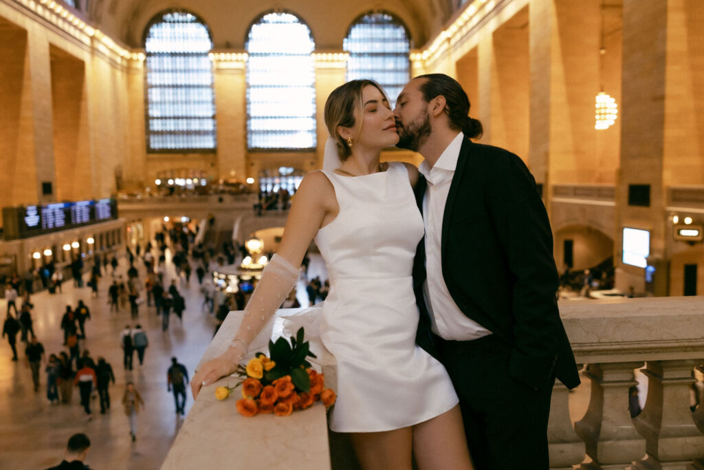 Newlywed couple posing for photos at Grand Central Terminal, surrounded by the iconic architecture and vibrant energy of NYC