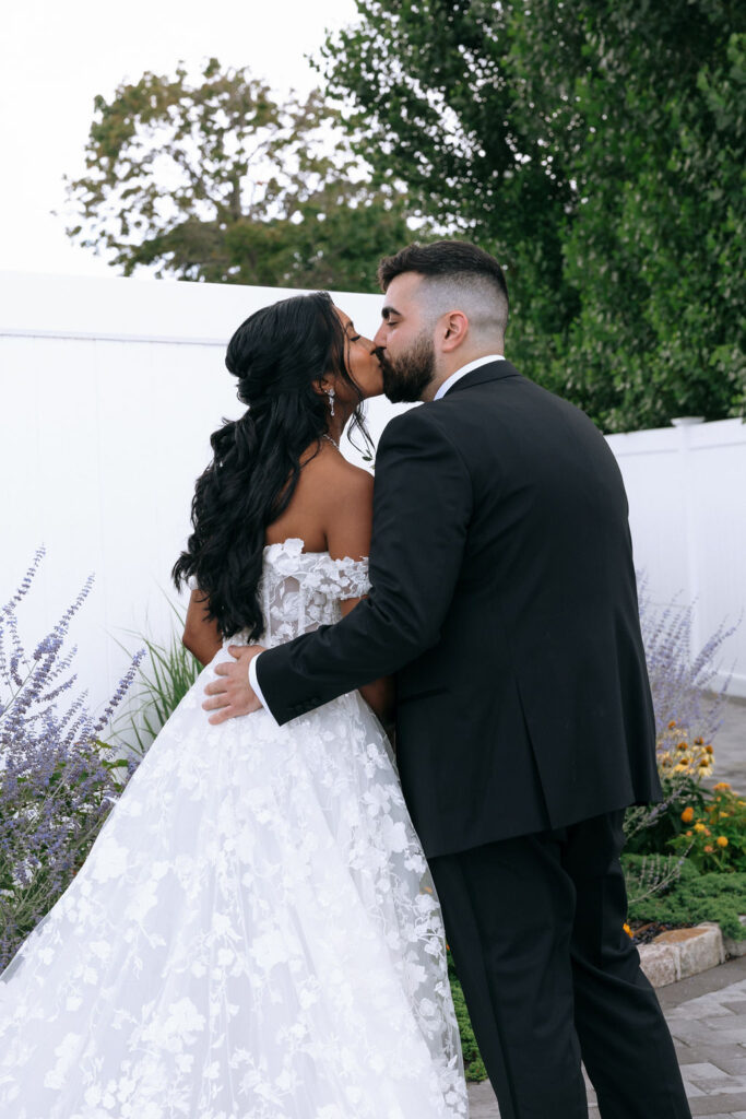 Romantic kiss shared by bride and groom after their first look, captured in a candid, intimate moment during their wedding day
