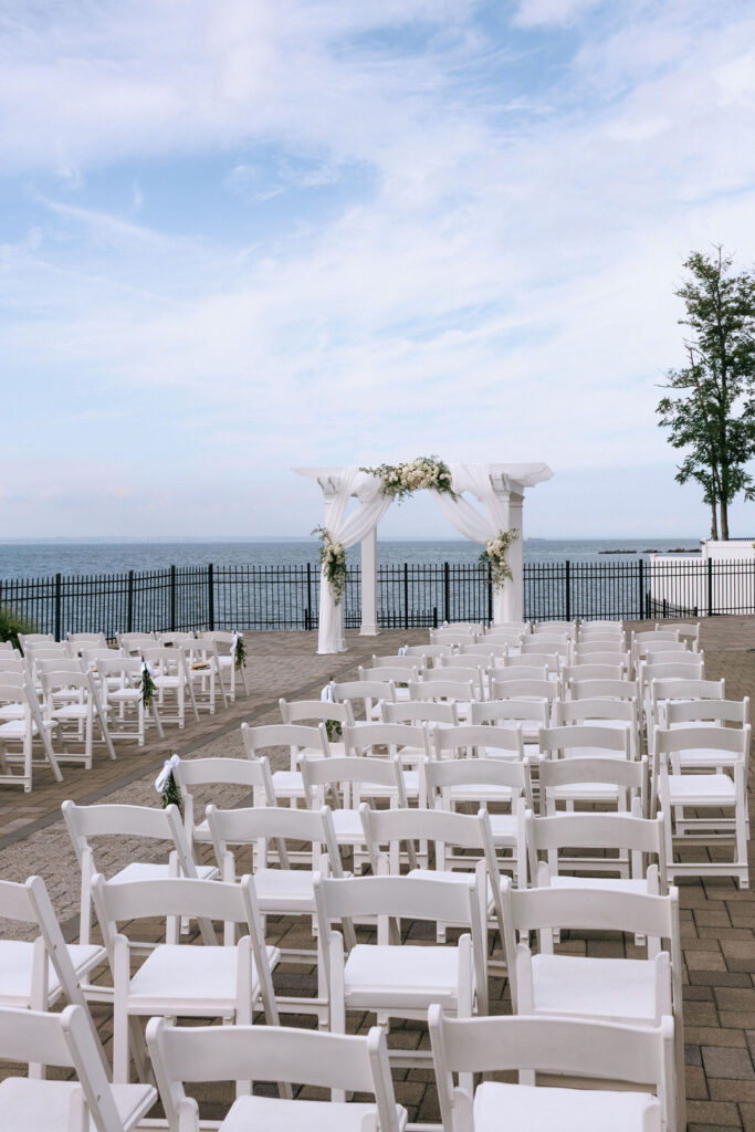 Romantic waterfront wedding ceremony setup, featuring elegant decor for a joyful, in-love couple's intimate celebration
