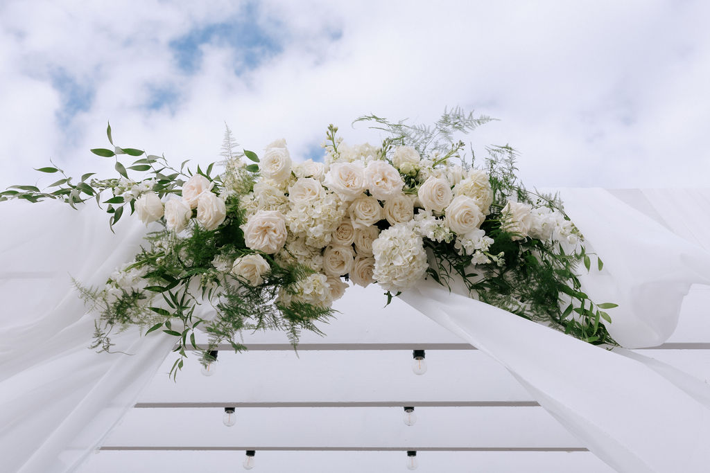 Wedding ceremony arch decorated with lush flowers and greenery, creating a romantic and elegant backdrop for the couple’s vows.
