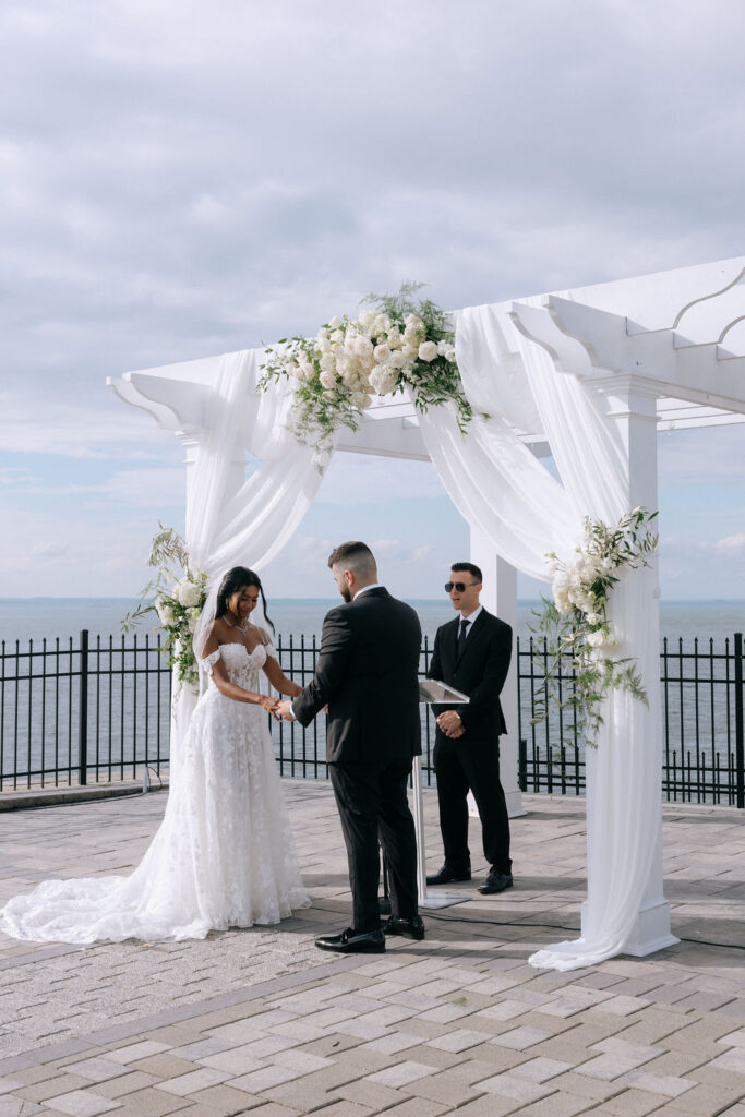 Bride and groom holding hands during their wedding ceremony, sharing a tender and romantic moment as they exchange vows.