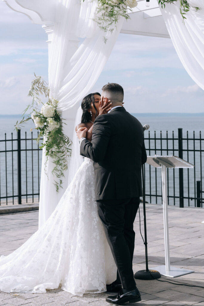 Bride and groom sharing their first kiss as a married couple, capturing a romantic and joyful moment during the wedding ceremony