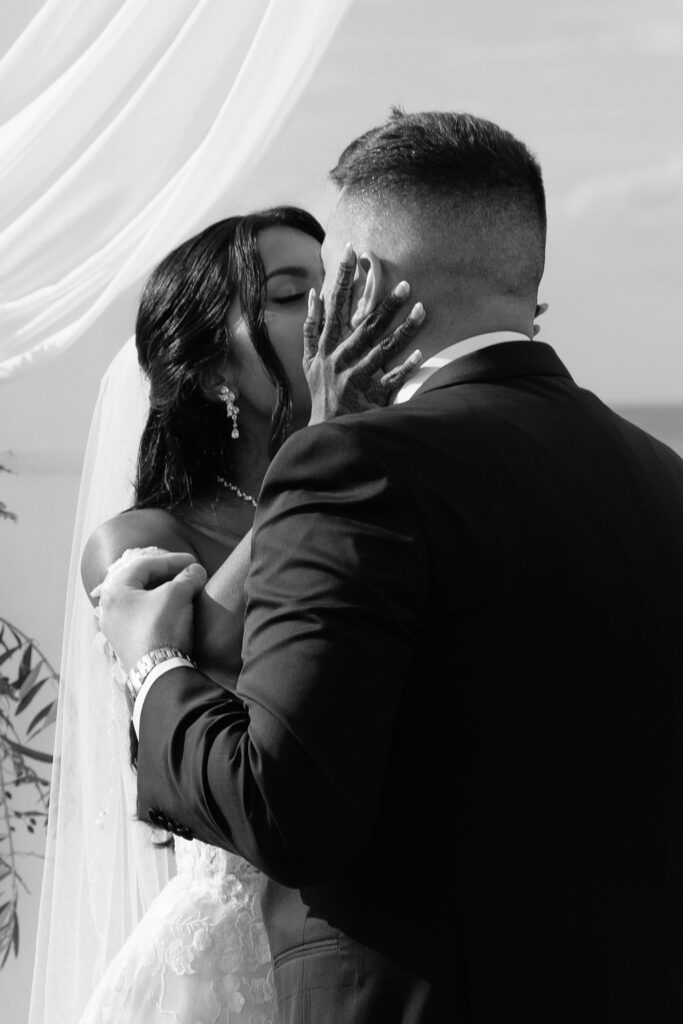 Bride and groom sharing a passionate first kiss as husband and wife, celebrating their love during the wedding ceremony