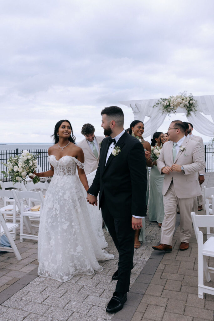 Bride, groom, and bridal party walking together after the ceremony, sharing joyful smiles and laughter in a candid, celebratory moment