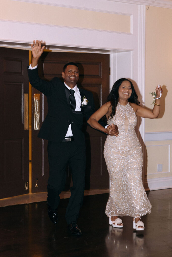 Parents making a joyful entrance at the wedding reception, greeted with cheers and applause, setting a celebratory tone for the evening.