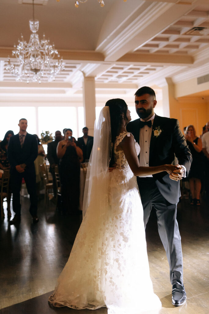 Bride and groom sharing a joyful first dance, surrounded by love and celebration on the dance floor