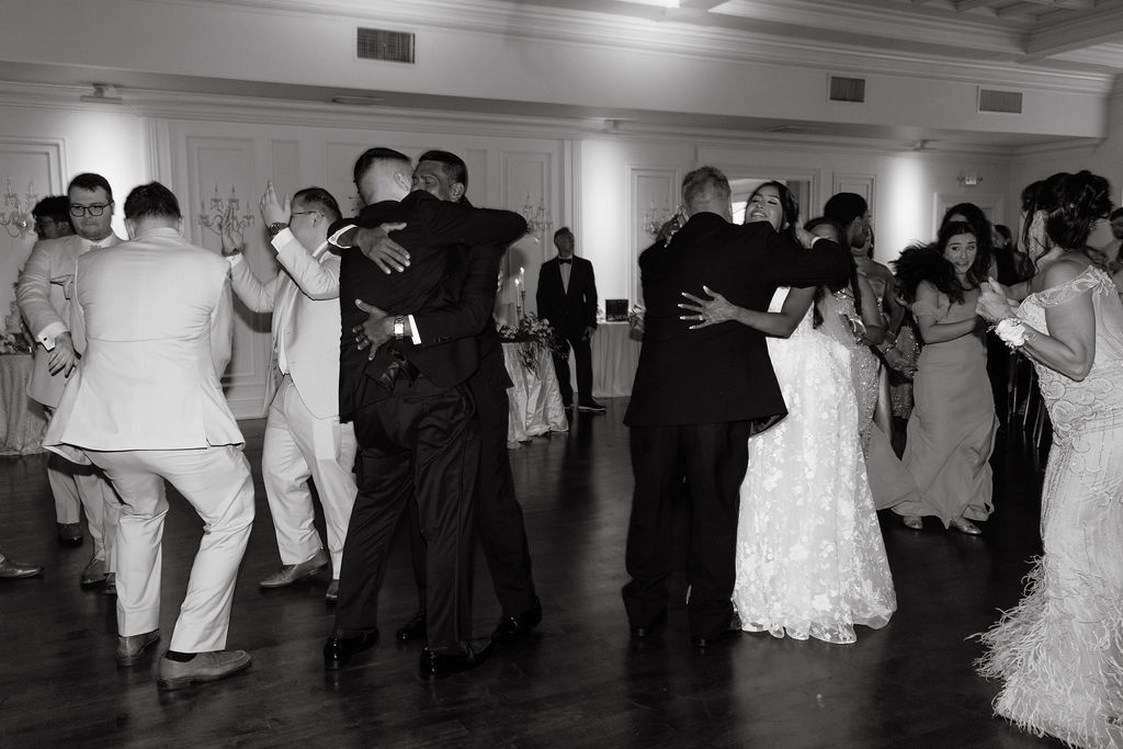 Bride and groom hugging their parents after the first dance, sharing an emotional and heartfelt moment during the wedding celebration