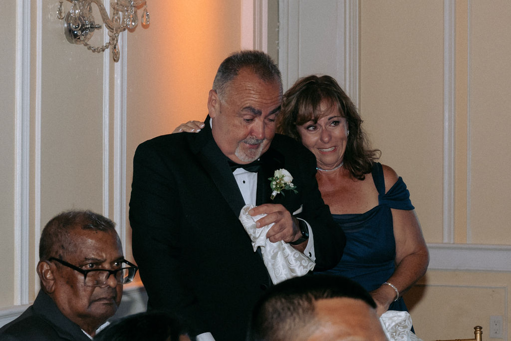 Emotional moment of the groom dancing with his mom, with his dad observing proudly during the wedding celebration.
