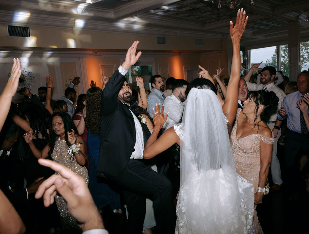 Guests dancing and celebrating on the lively wedding dance floor, filled with energy, laughter, and joy as they enjoy the celebration