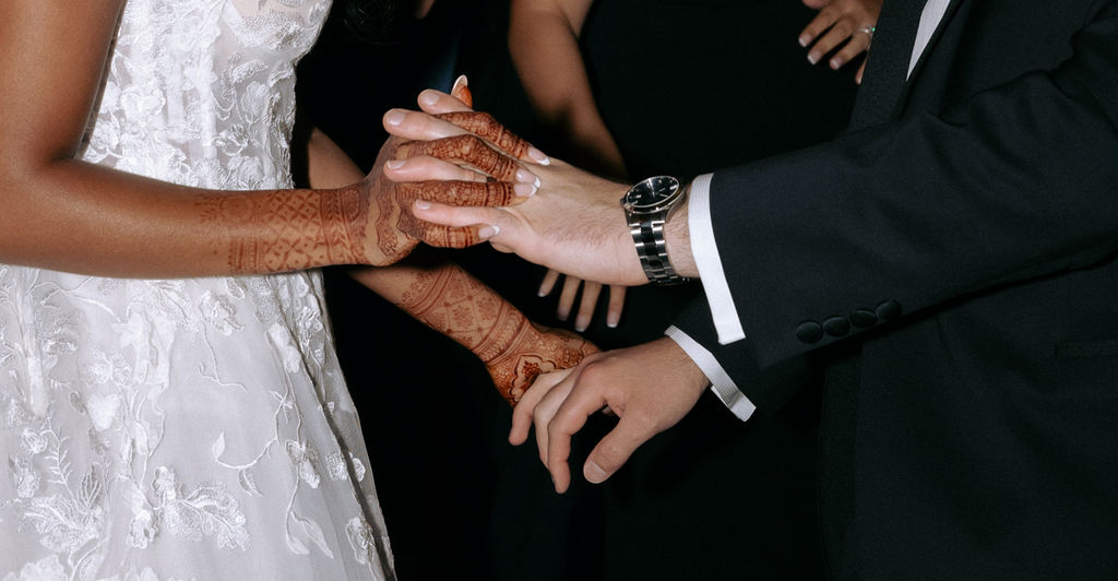 Bride and groom holding hands, symbolizing their love and connection during their wedding ceremony.