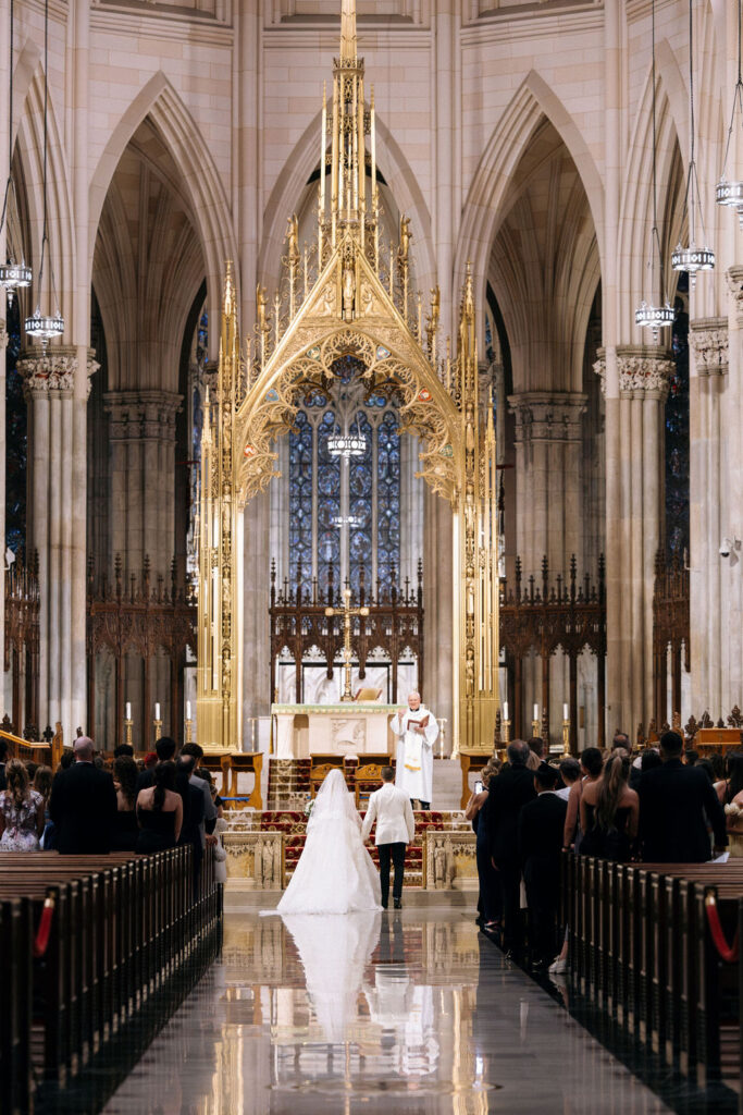 A bride and groom standing at the altar of a grand cathedral during their luxurious NYC wedding ceremony.