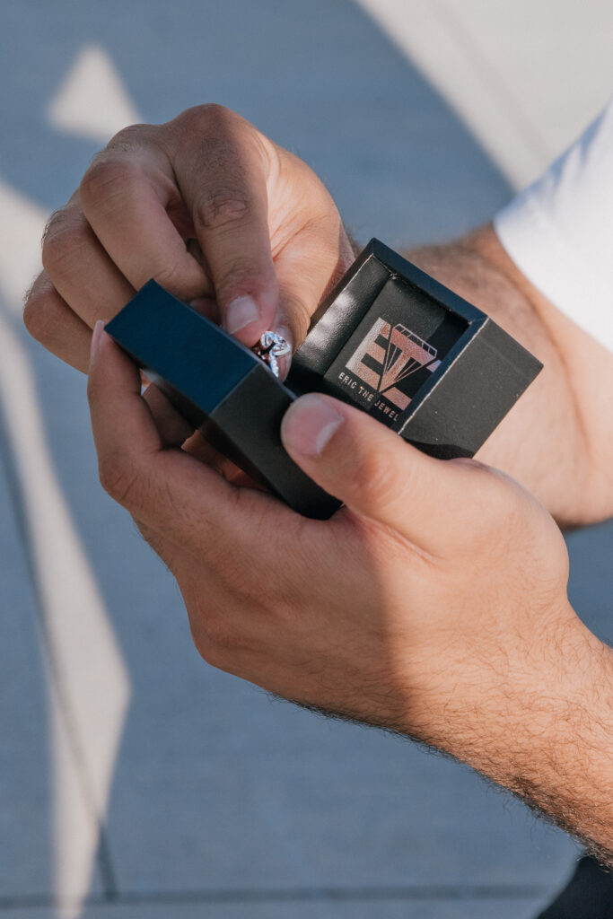 Groom opens an engagement ring box with a custom design from Eric The Jeweler during a proposal.