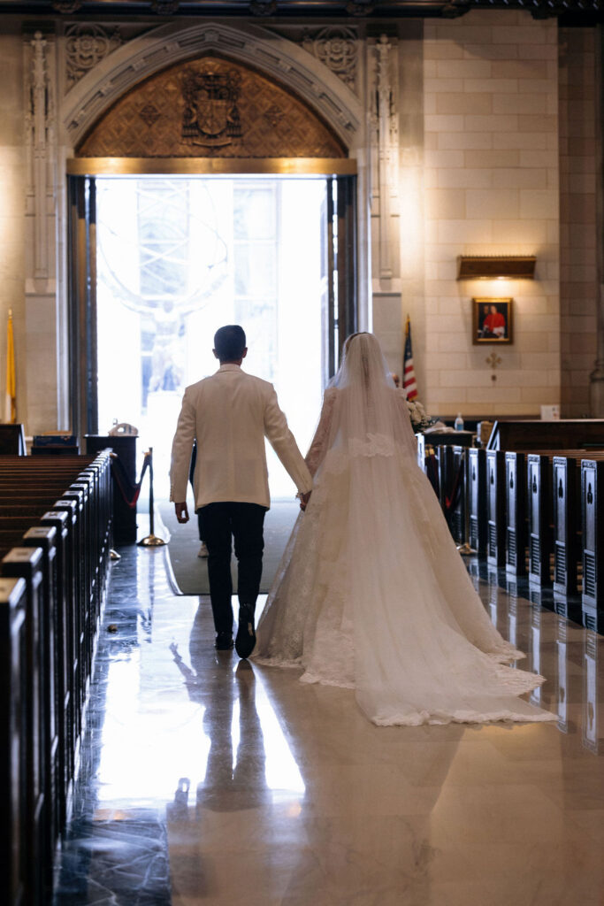 The bride and groom walk hand-in-hand down the aisle, leaving the grand Saint Patricks Cathedral NYC as newlyweds.