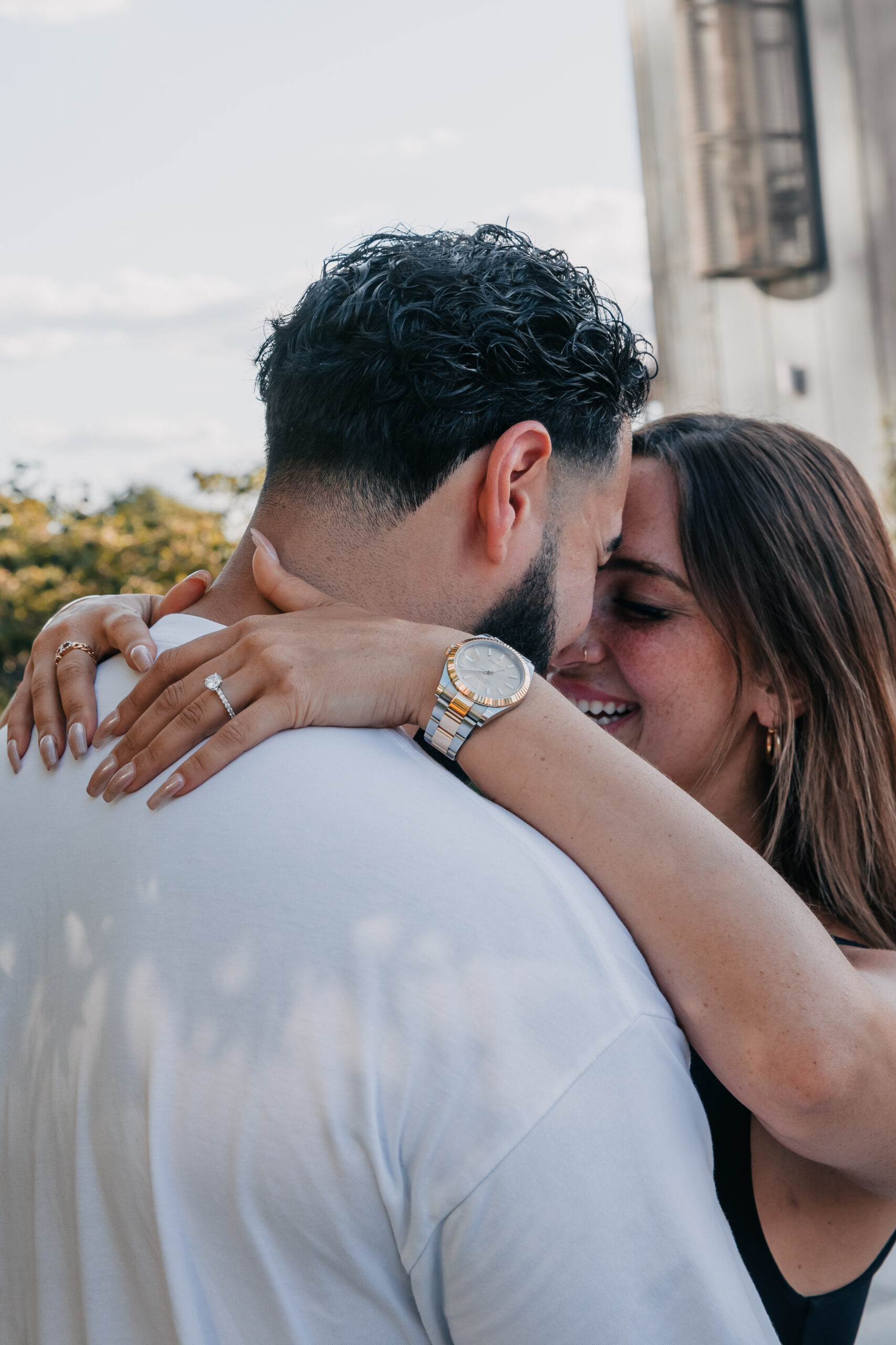 Close-up of a bride and groom sharing an intimate embrace, featuring her diamond engagement ring and her luxury wristwatch.