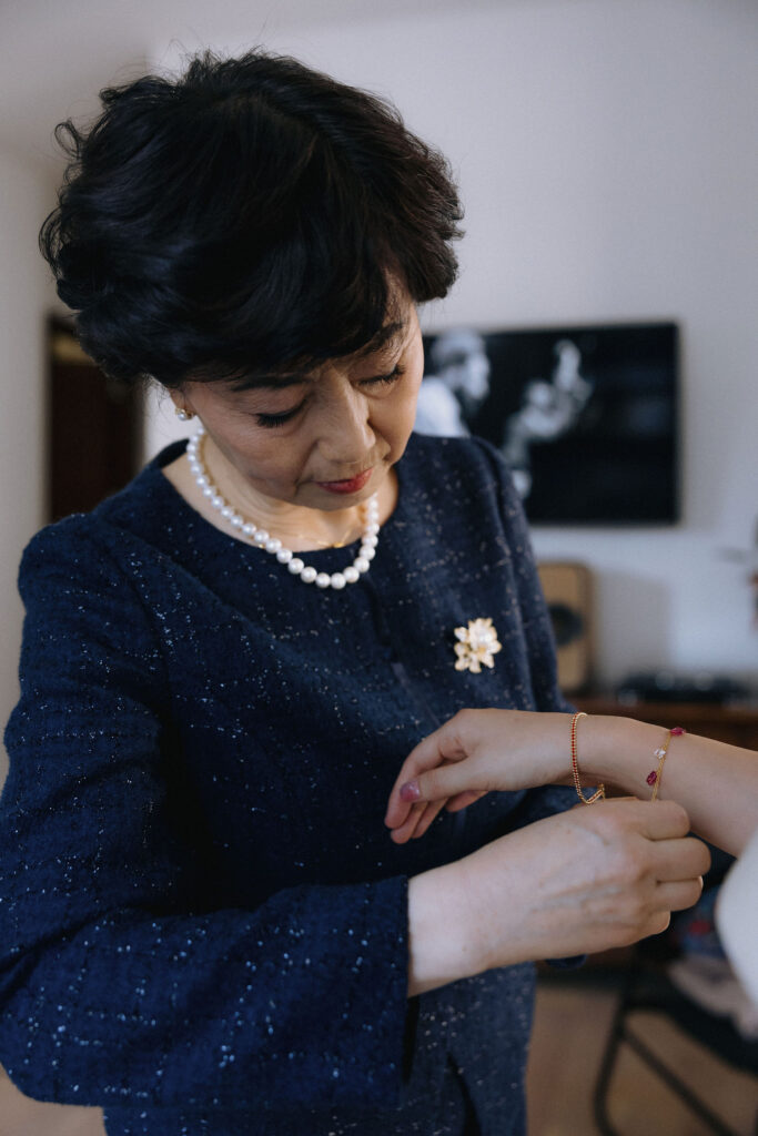 A close-up of a mother gently helping her daughter fasten a delicate bracelet, a touching moment captured in soft lighting before the wedding.