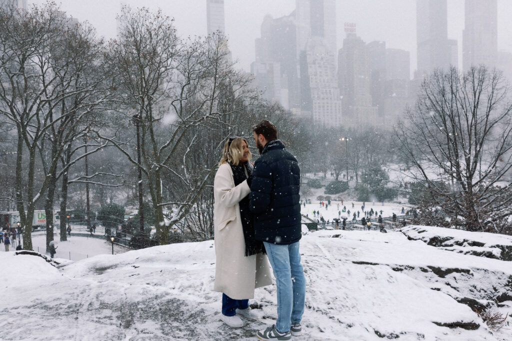 Couple during a surprise proposal in the snow with a stunning skyline view, capturing an intimate and joyful momen