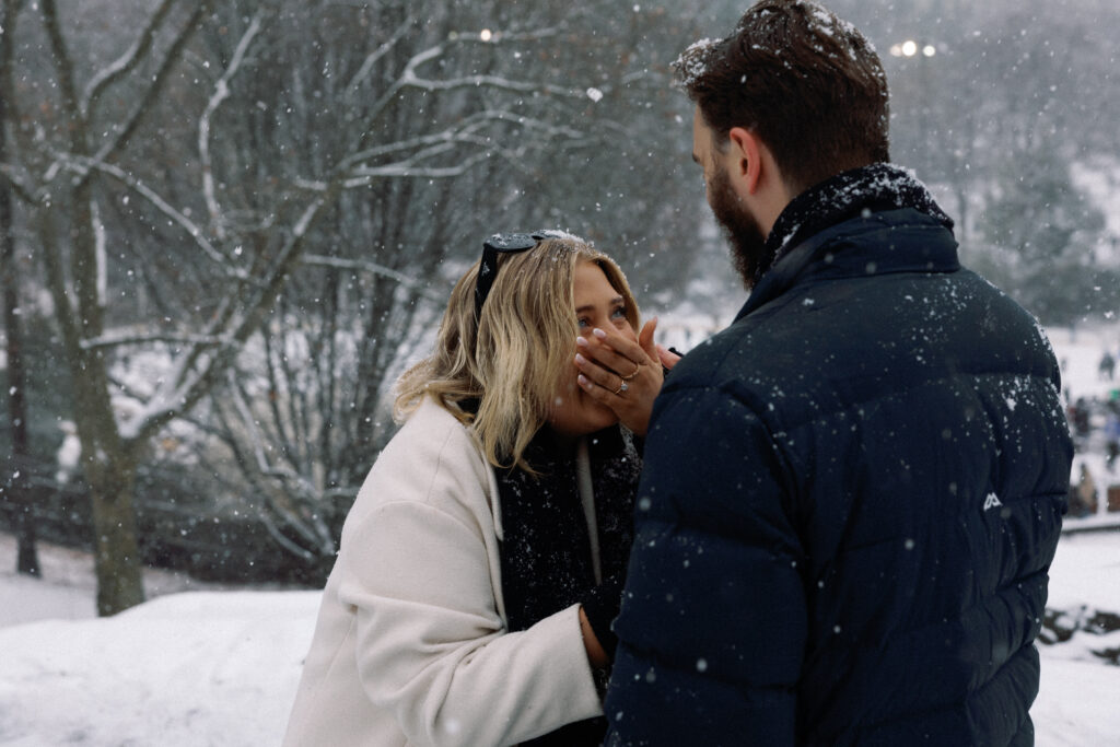 Couple moment as she laughs in surprise, covering her mouth with her hand, radiating happiness and joy