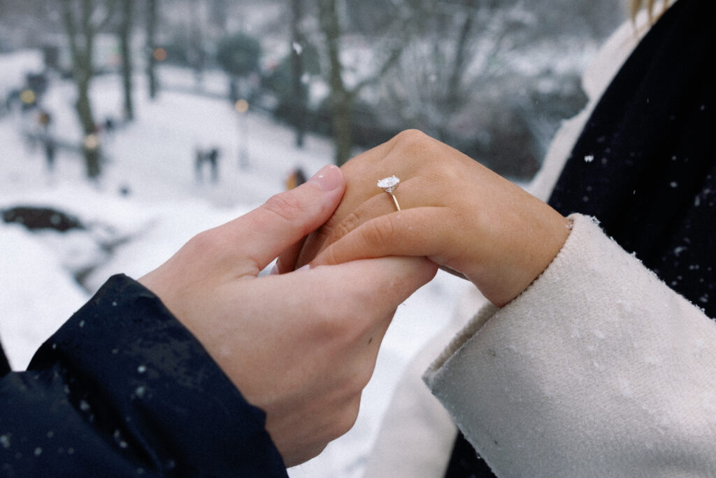 Close-up of a couple holding hands, showcasing the engagement ring in a romantic and intimate moment