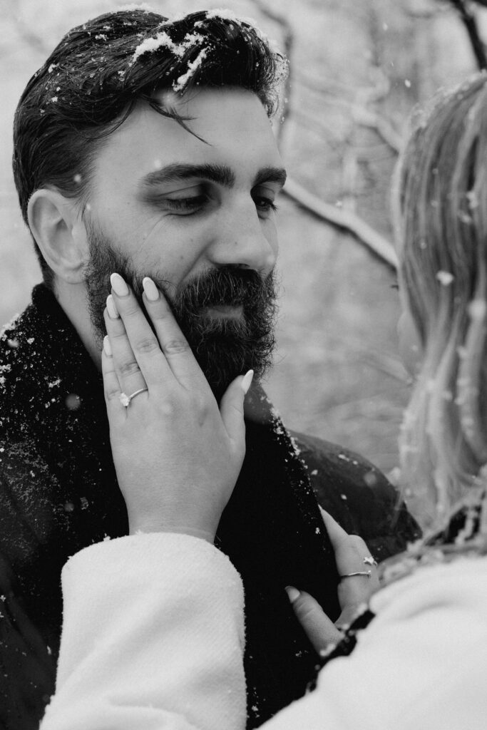 Close-up of a hand with an engagement ring gently resting on a beard, symbolizing love and intimacy.