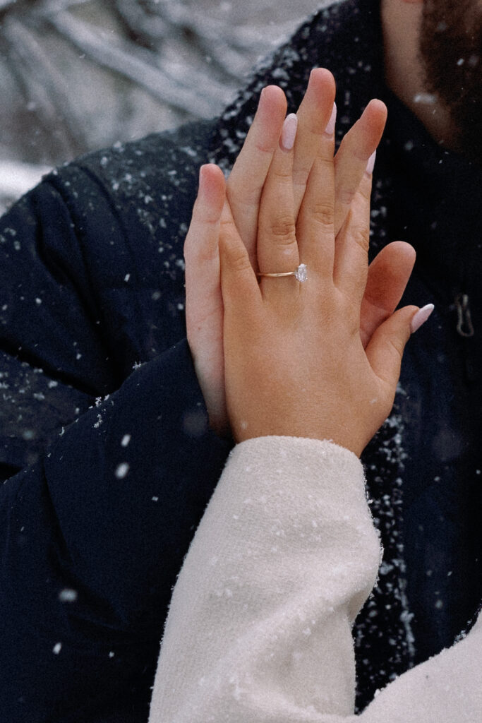 Close-up of intertwined hands with an engagement ring, symbolizing love and commitment.