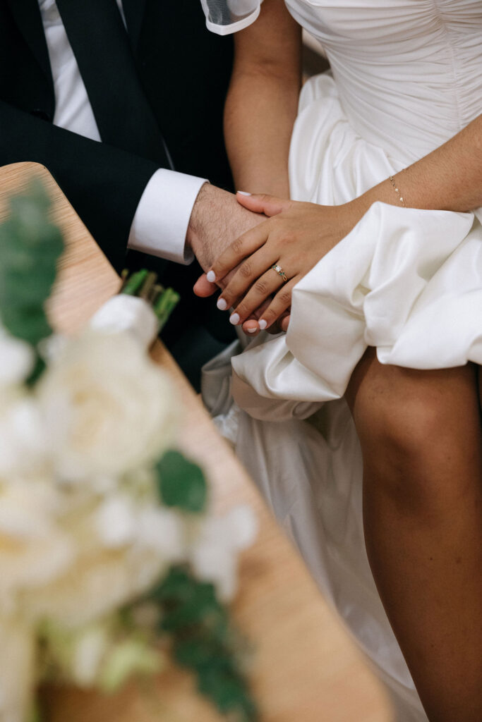 Close-up of the bride's hand resting on the groom's, highlighting her engagement ring and delicate wedding dress during their Brooklyn City Hall elopement