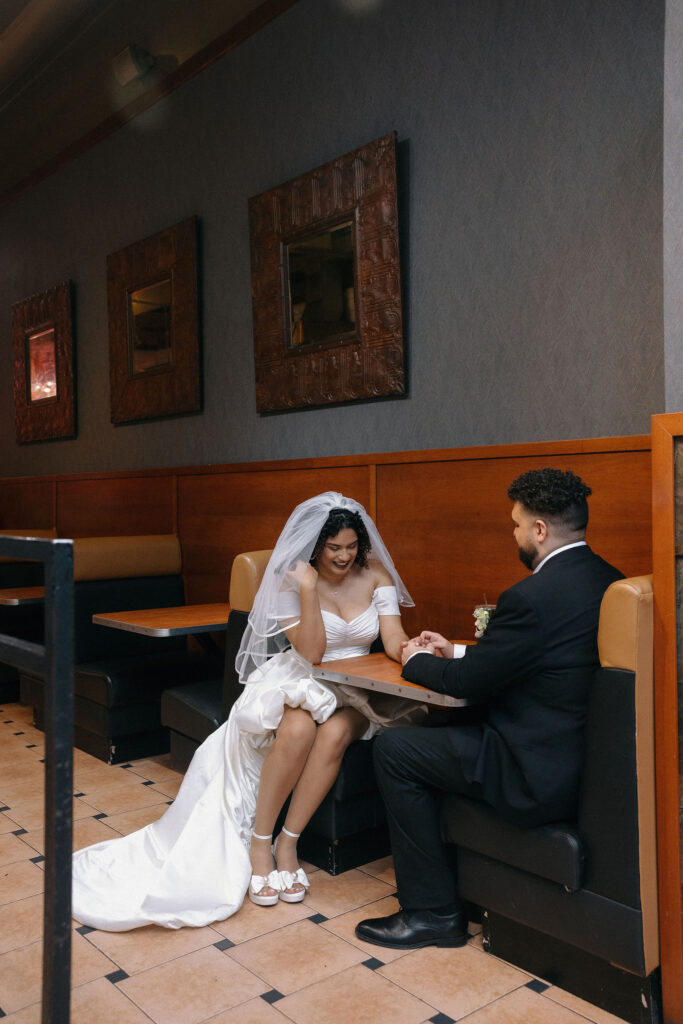 Bride and groom ordering food at a Brooklyn pizza shop, enjoying a relaxed moment after their NYC elopement