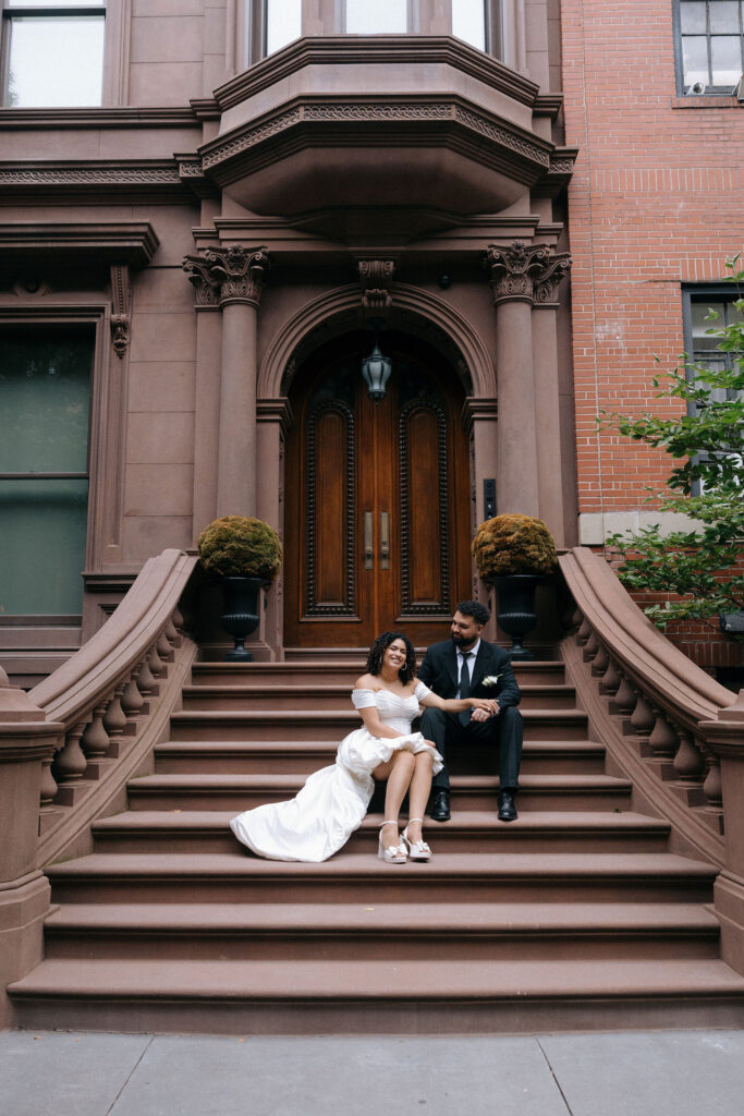 Bride and groom sitting together on the steps of a Brooklyn brownstone, sharing a joyful and relaxed moment during their NYC elopement