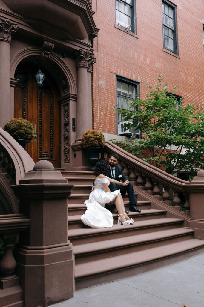 Bride and groom sitting on the steps of a Brooklyn brownstone, sharing a relaxed and intimate moment during their NYC elopement