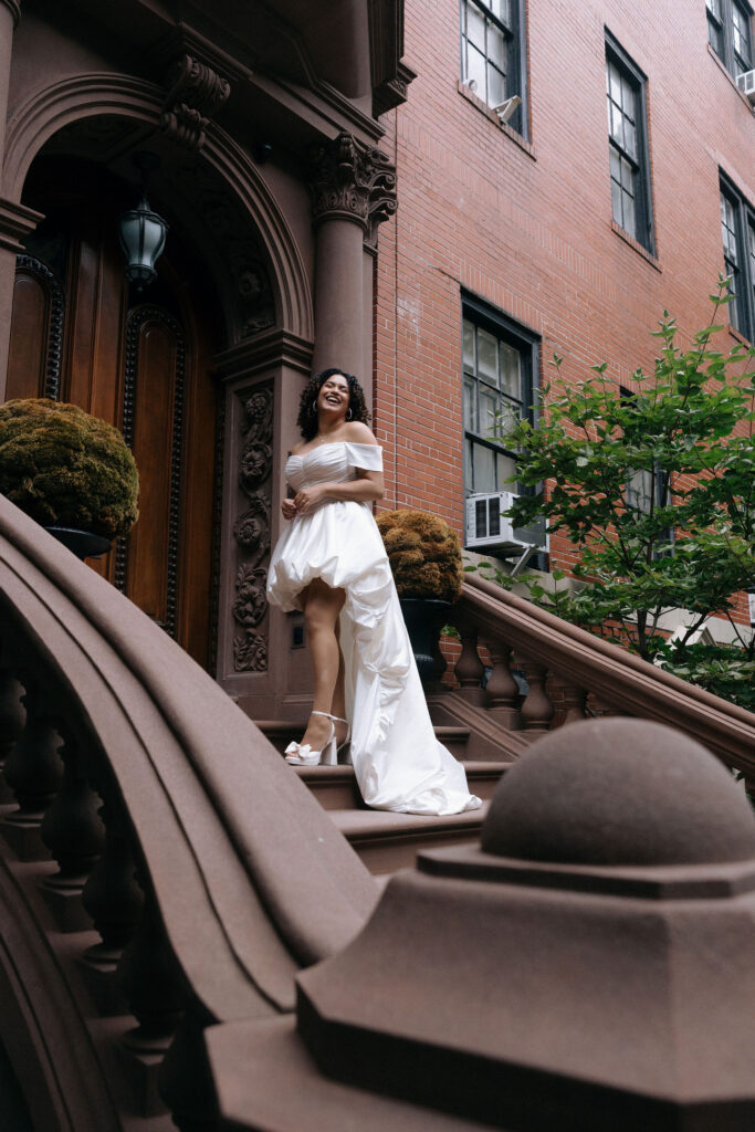 Bride standing confidently on the steps of a Brooklyn brownstone, showcasing her elegant dress during an NYC elopement