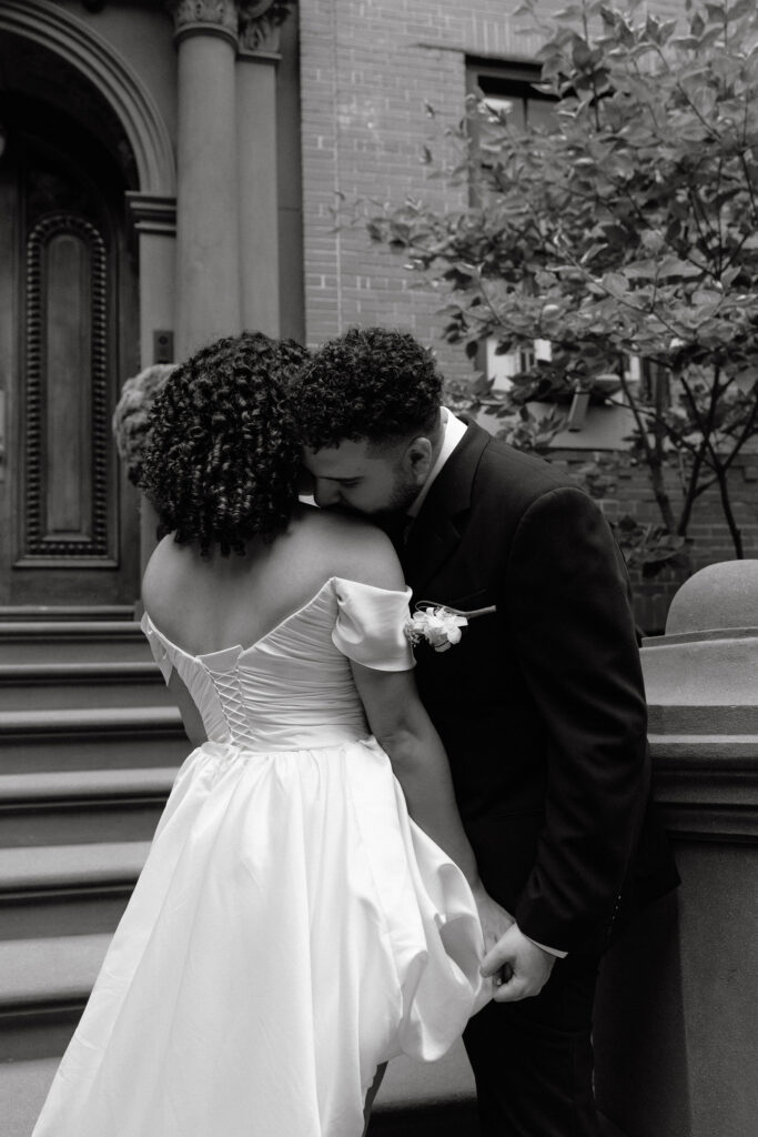 Close-up black-and-white photo of a bride and groom sharing a tender embrace on the steps of a Brooklyn brownstone during their NYC elopemen