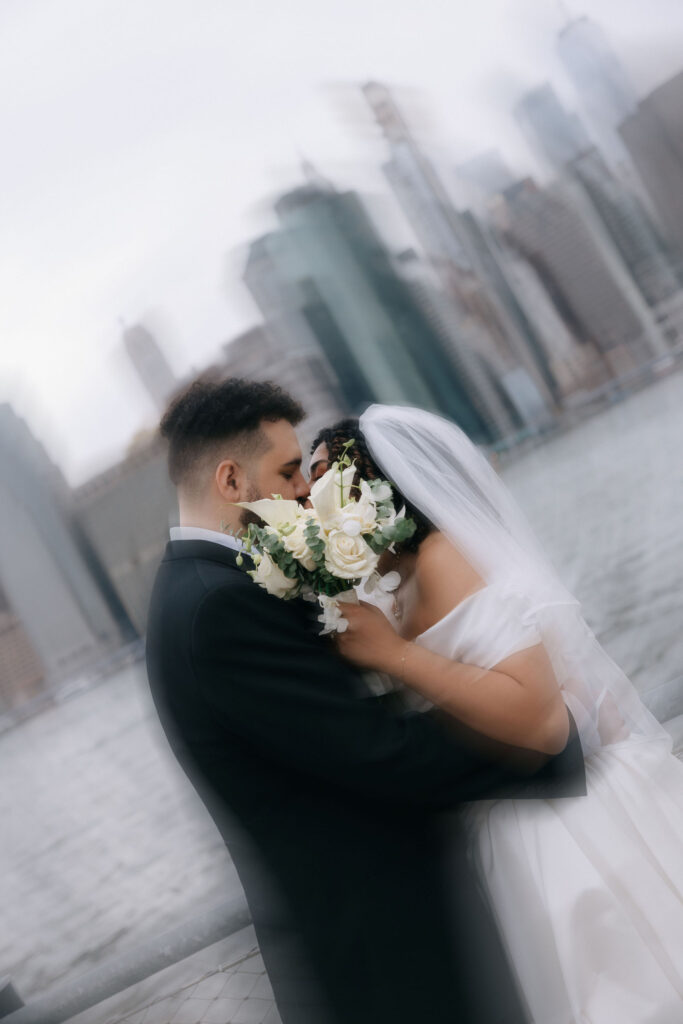 Couple sharing an intimate moment with a soft, dreamy blur effect, Manhattan skyline faintly visible in the background.