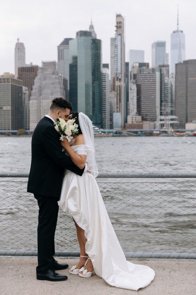 Couple sharing an intimate embrace with the Manhattan skyline in the background, captured along the waterfront