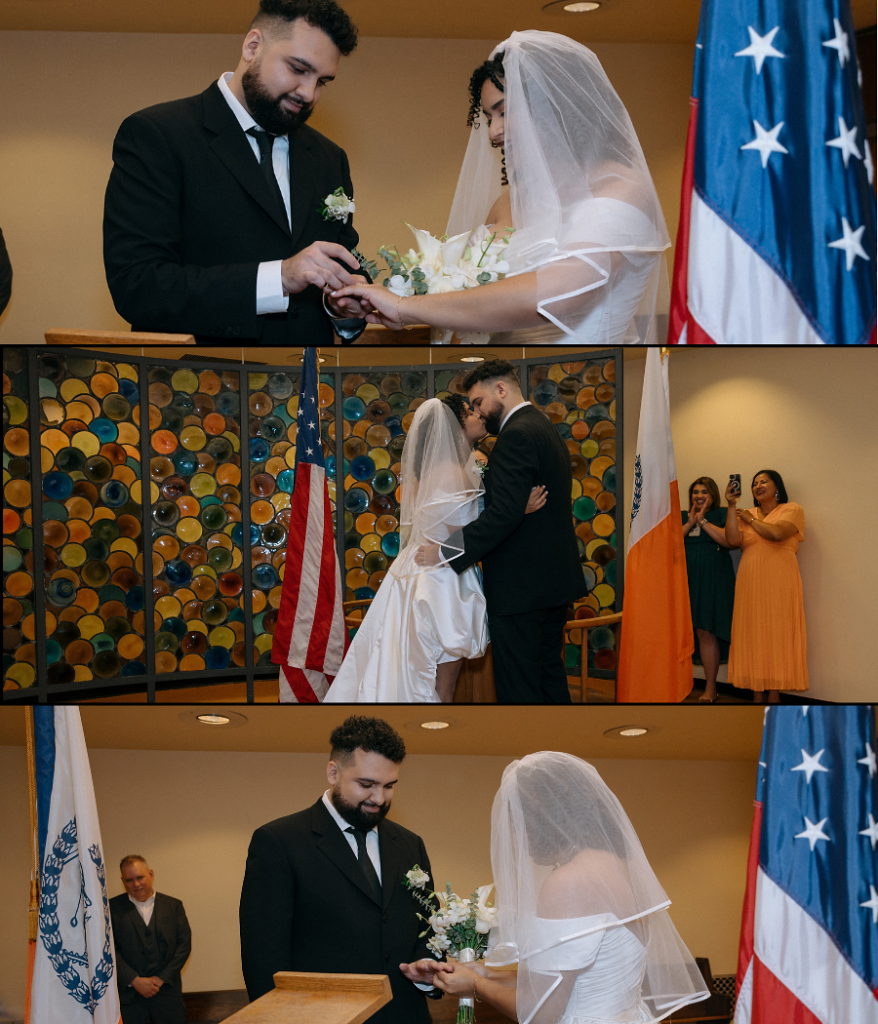 Brooklyn City Hall elopement ceremony: groom places a ring on the bride's hand, the couple shares a kiss, and the bride holds her bouquet as family looks on