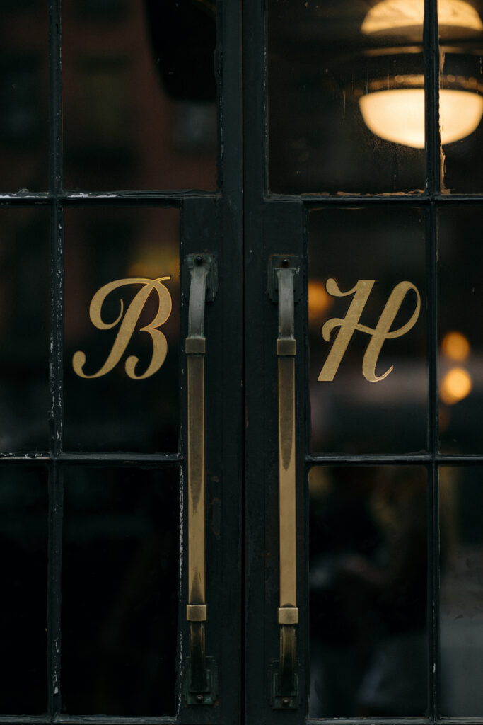 The iconic black and gold entrance doors of the Bowery Hotel, featuring elegant "B H" lettering, set the tone for a timeless and stylish New York City wedding.