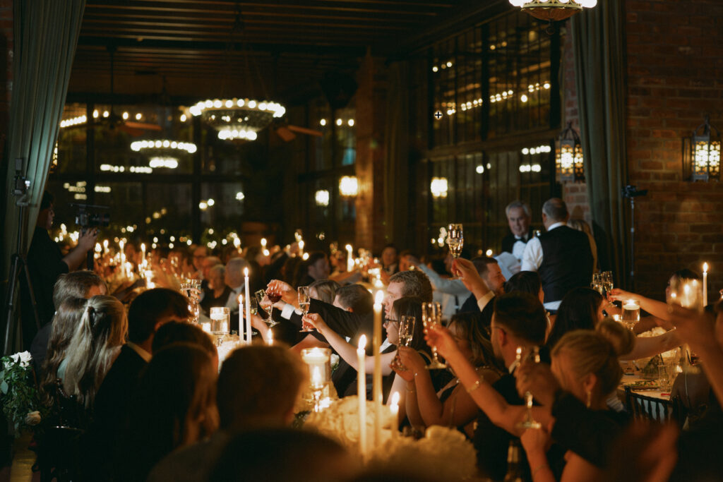 Wedding guests raise their glasses for a heartfelt toast at the Bowery Hotel, surrounded by candlelight, vintage chandeliers, and an intimate, romantic atmosphere.