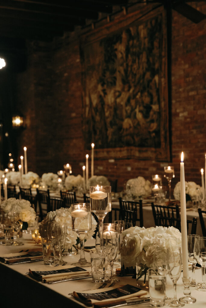 A beautifully set wedding reception table at the Bowery Hotel, featuring candlelit centerpieces, white floral arrangements, and an intimate vintage ambiance.