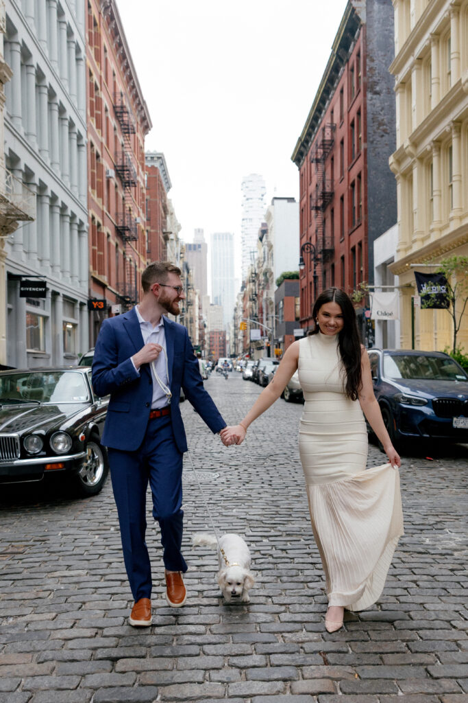 Bride and groom walking hand in hand down cobblestone street in Tribeca during their NYC wedding

