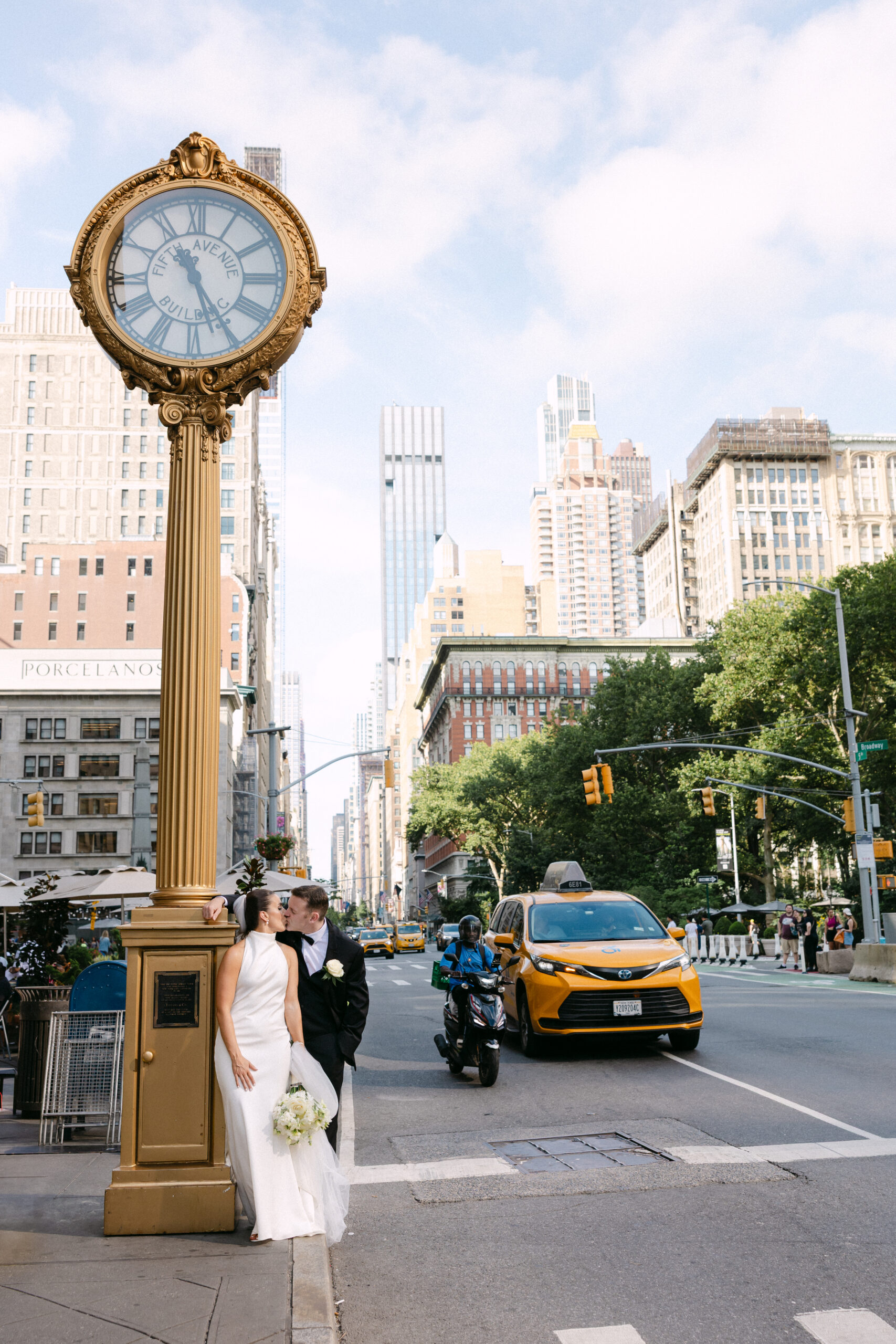 Bride and groom crossing 5th Avenue near Pulitzer Fountain in NYC with yellow cab in background